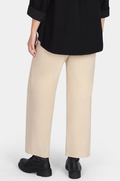 Woman wearing a black top and beige pants on a white background