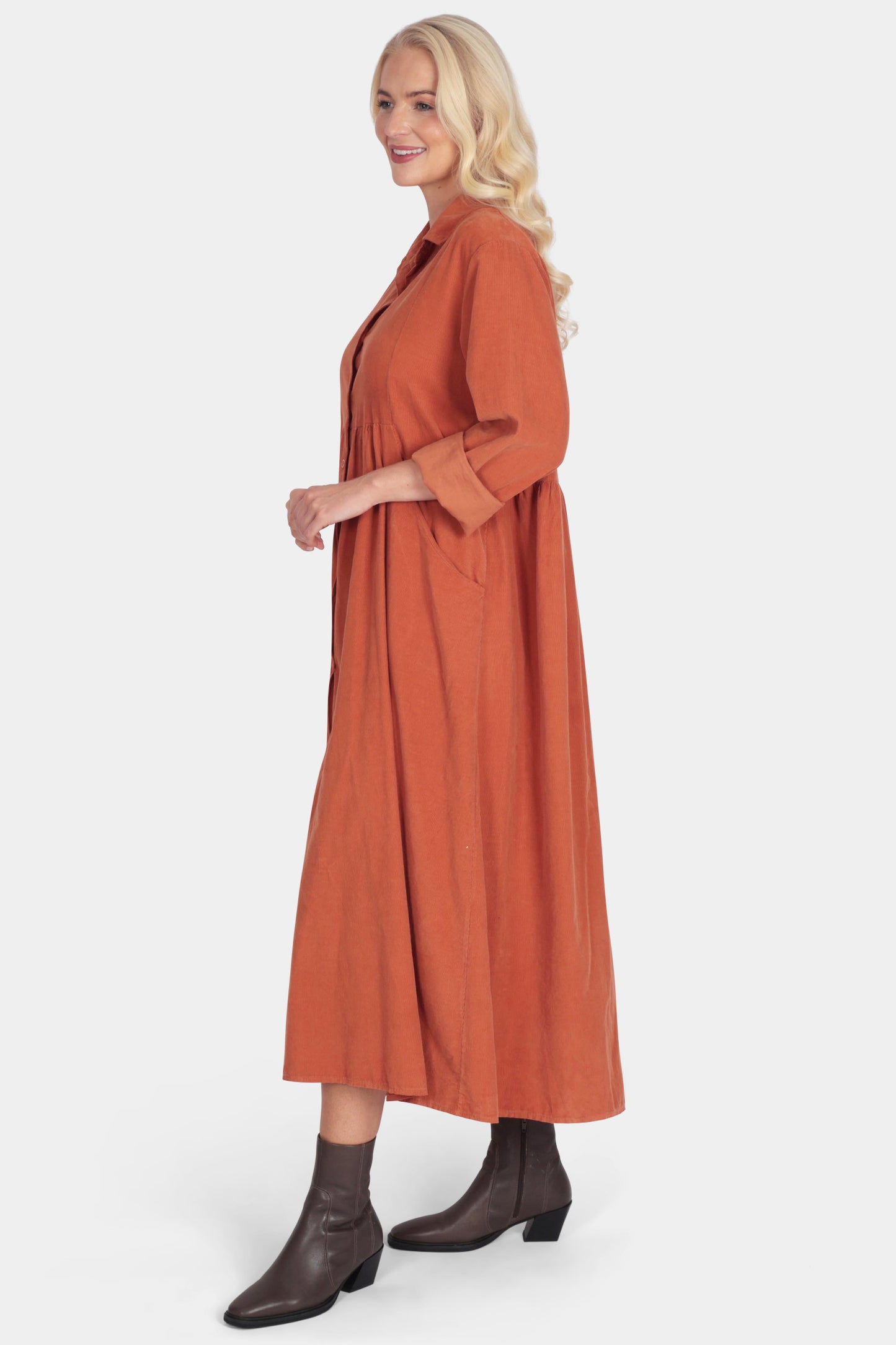 Woman wearing a long rust-colored dress on a white background