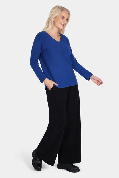 Woman wearing a blue sweater and black pants on a white background