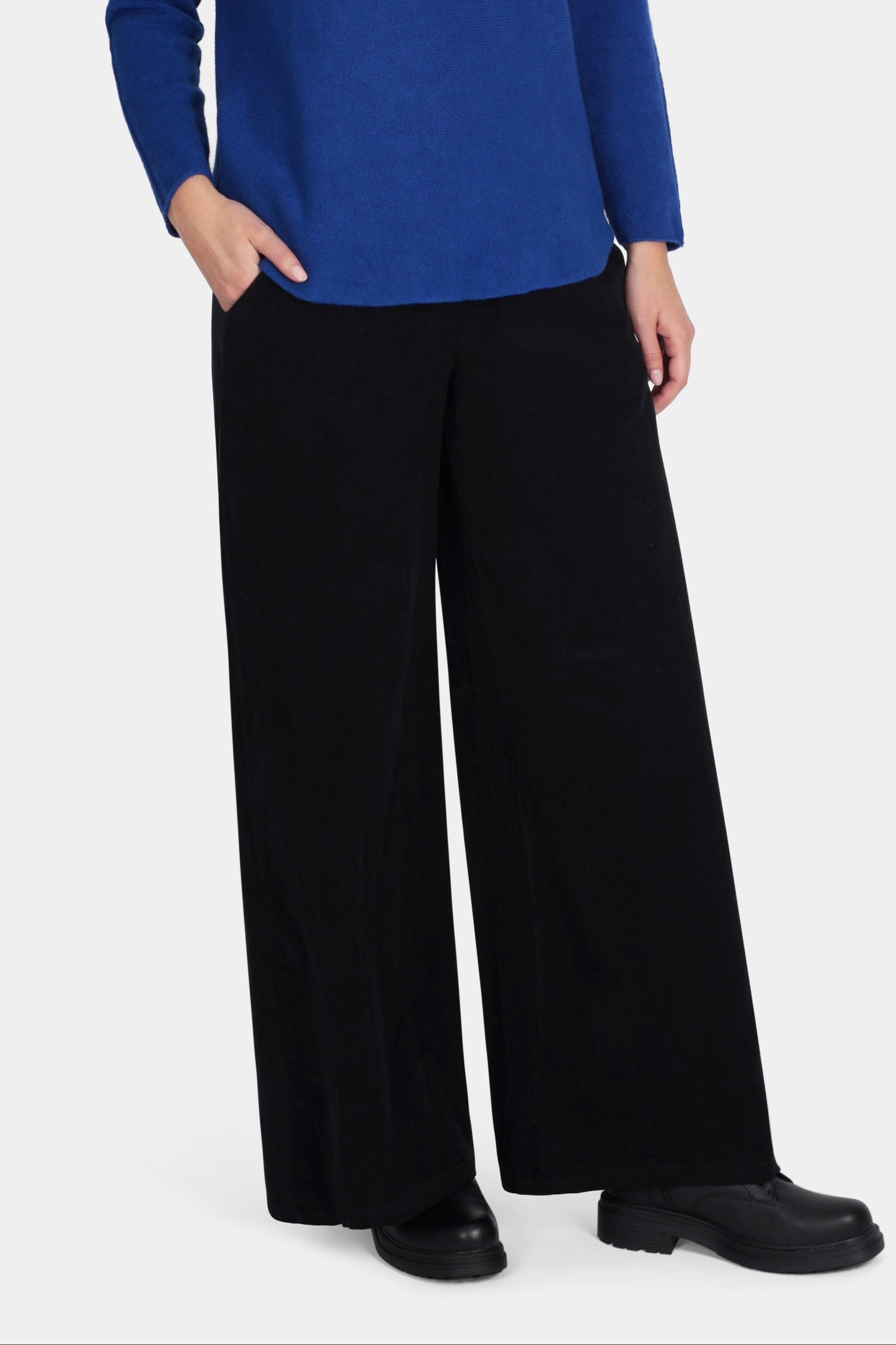 Woman wearing a blue sweater and black pants on a white background