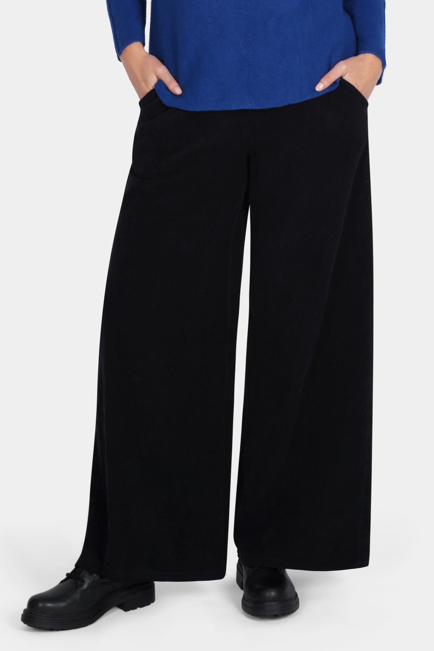 Woman wearing a blue sweater and black pants on a white background