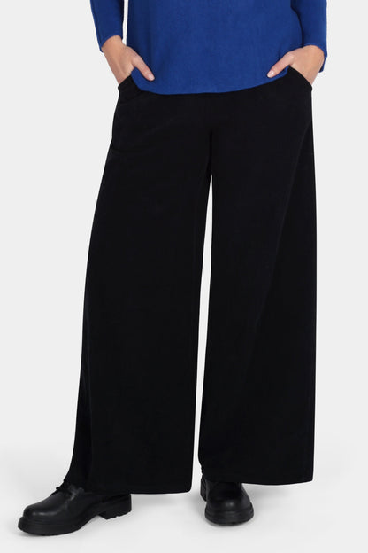 Woman wearing a blue sweater and black pants on a white background