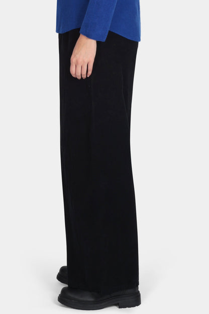 Woman wearing a blue sweater and black pants on a white background