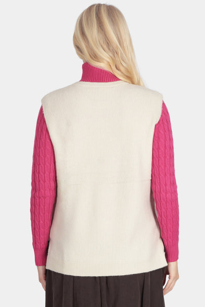 Person wearing a pink long-sleeve shirt, cream vest, and brown skirt on a white background