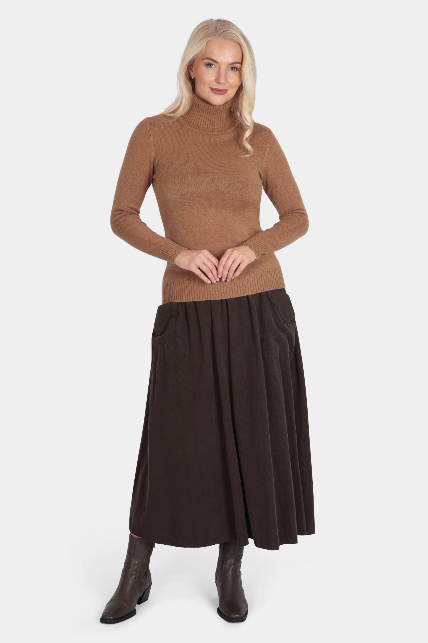 Woman wearing a brown turtleneck sweater and dark brown skirt on a white background