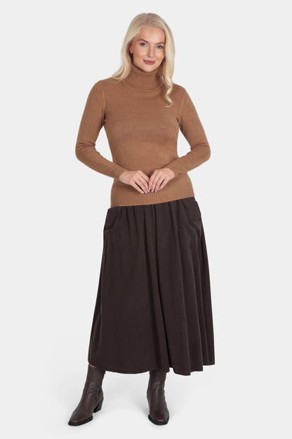 Woman wearing a brown turtleneck sweater and dark brown skirt on a white background