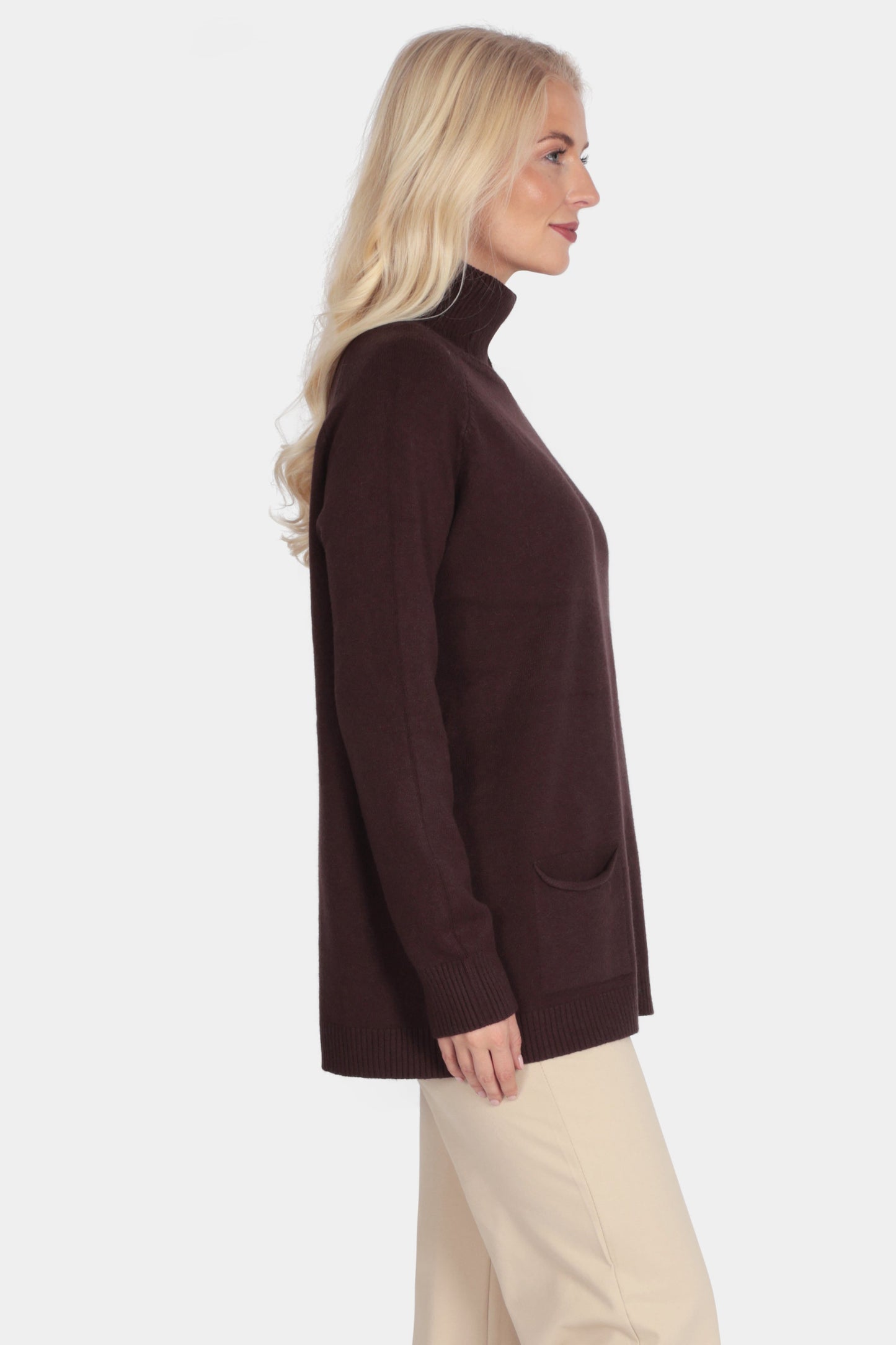 Woman wearing a brown turtleneck sweater and beige pants on a white background