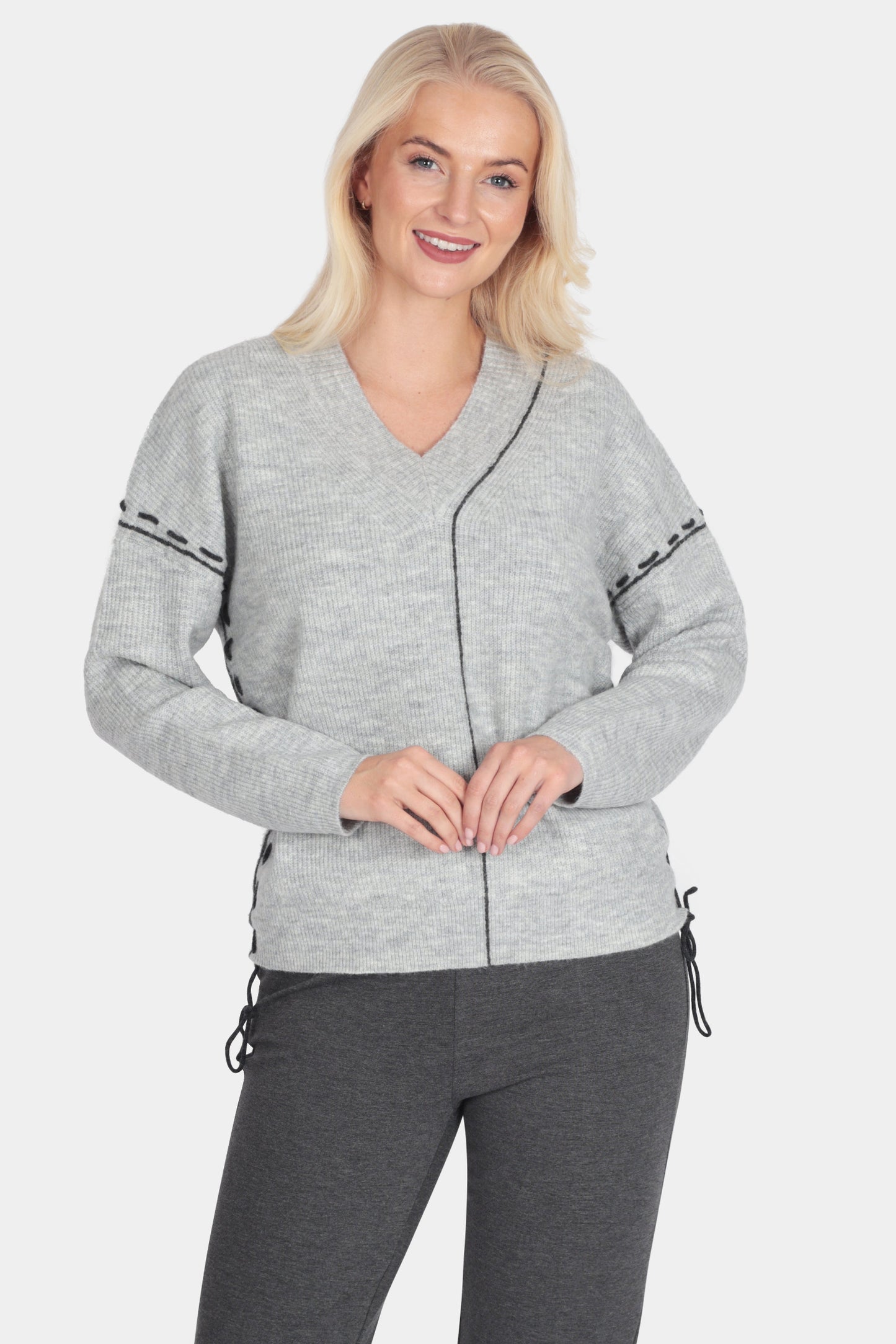 Woman wearing a gray cardigan and dark gray pants on a white background