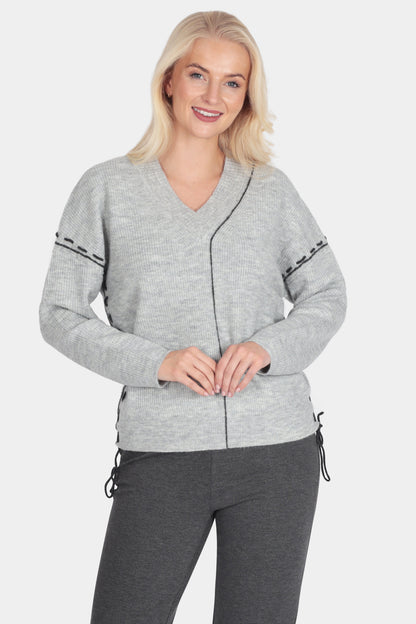 Woman wearing a gray cardigan and dark gray pants on a white background