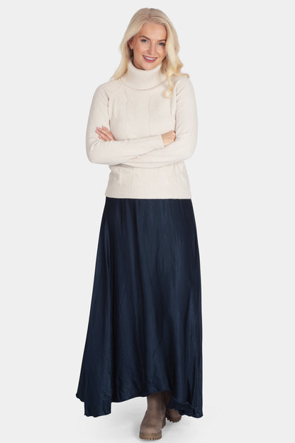 Woman wearing a white turtleneck sweater and navy blue skirt on a white background