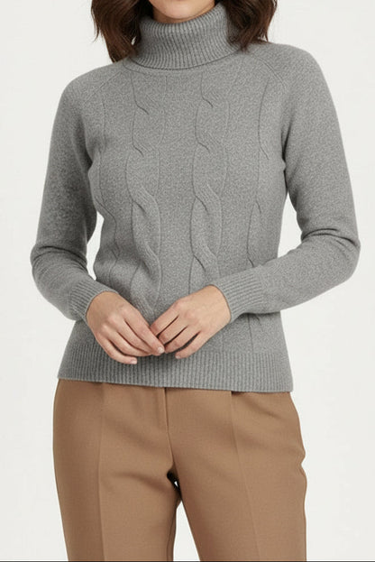 Woman wearing a gray cable knit sweater and beige pants on a white background