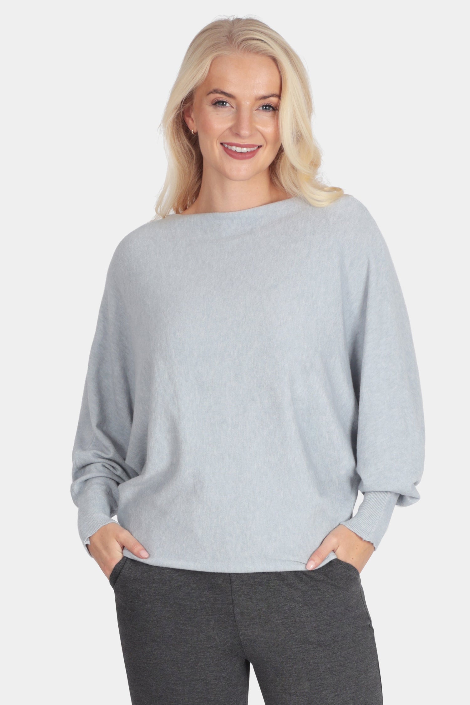 Woman wearing a light gray sweater and dark gray pants on a white background