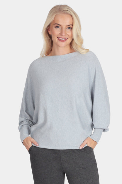 Woman wearing a light gray sweater and dark gray pants on a white background
