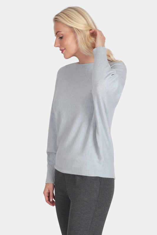 Woman wearing a light gray sweater and dark gray pants on a white background