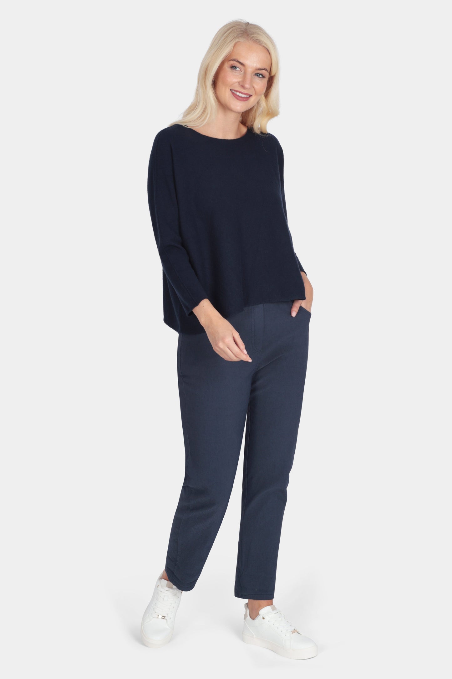 Woman wearing a navy blue outfit with white sneakers on a white background