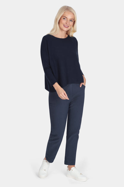 Woman wearing a navy blue outfit with white sneakers on a white background