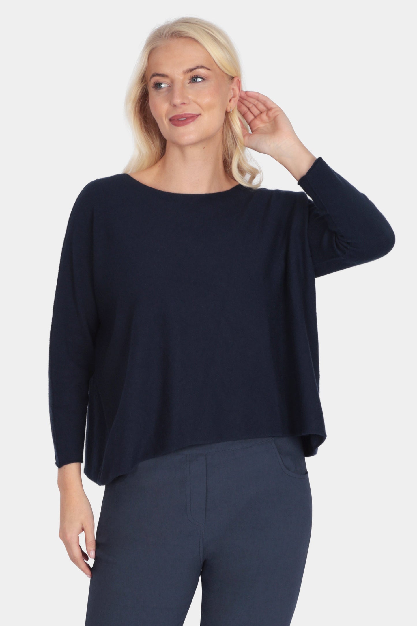 Woman wearing a navy blue outfit with white sneakers on a light gray background