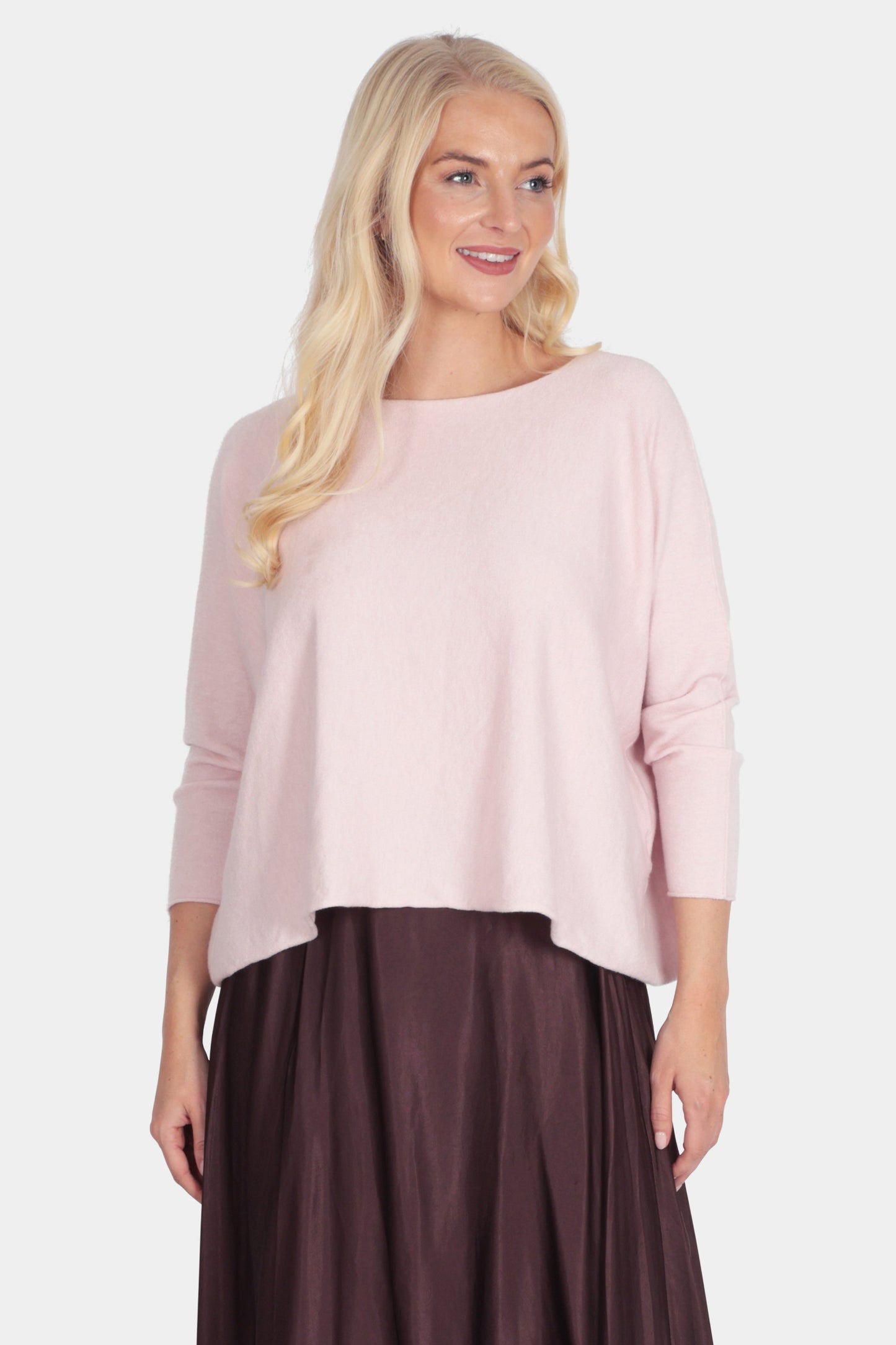 Woman wearing a light pink top and dark brown skirt on a white background