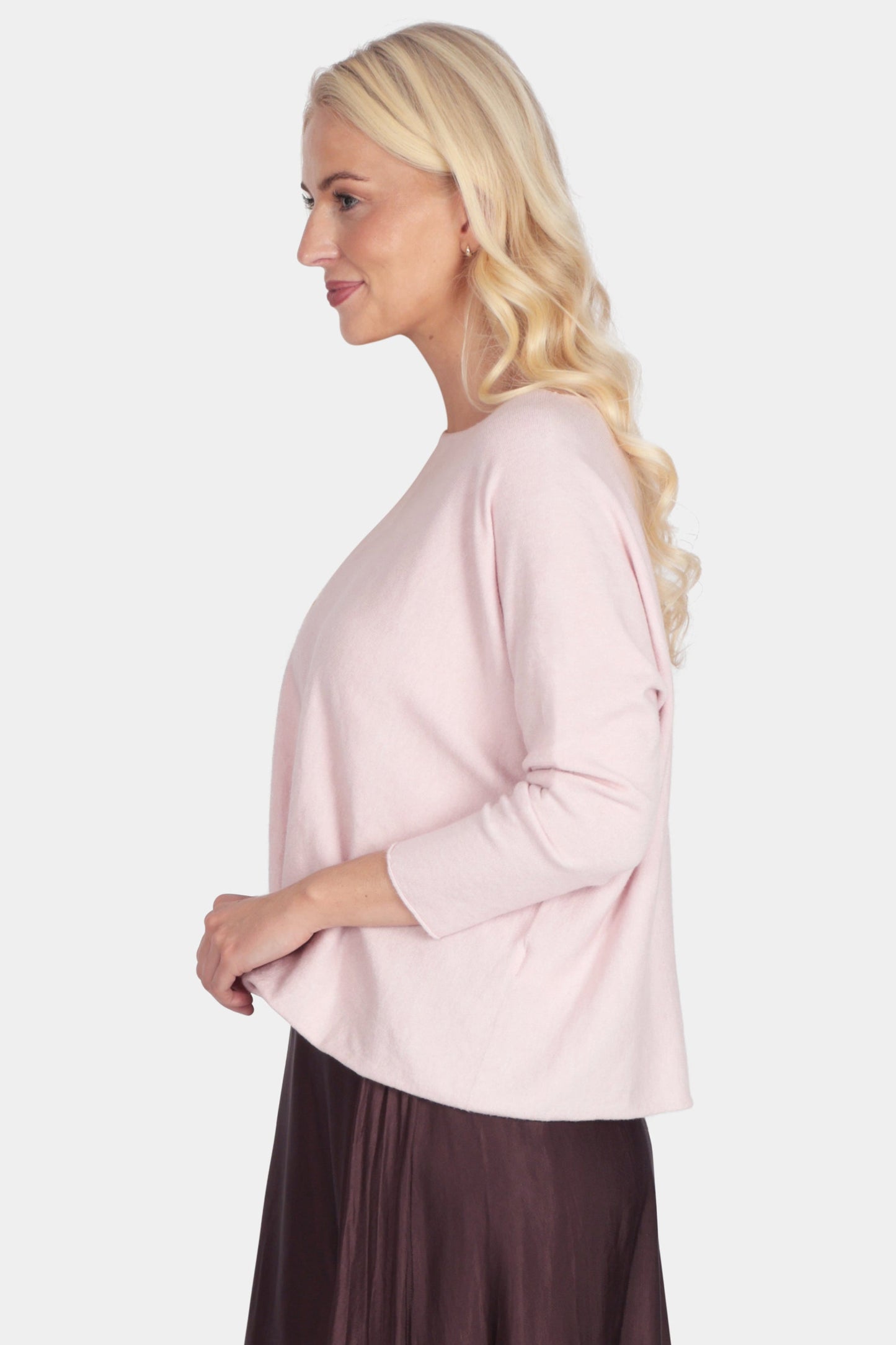 Woman wearing a light pink blouse and dark brown skirt on a white background