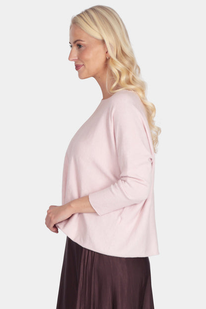 Woman wearing a light pink blouse and dark brown skirt on a white background