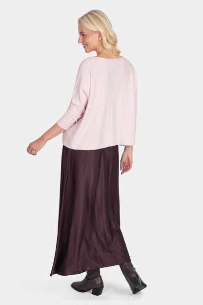 Woman wearing a light pink top and dark brown skirt on a white background