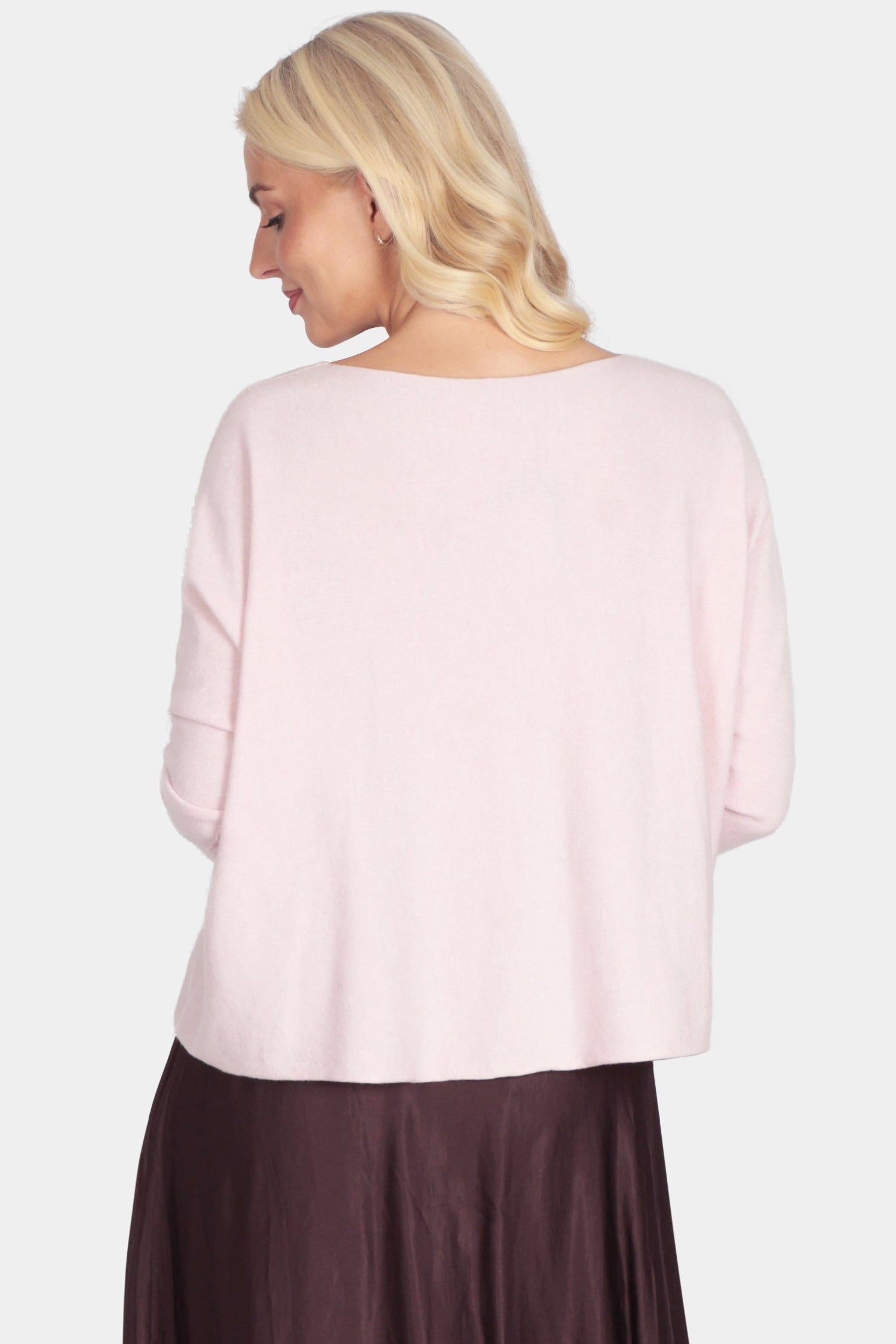 Woman wearing a light pink top and dark brown skirt on a white background