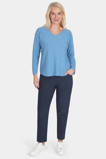 Woman wearing a blue sweater and navy pants on a white background