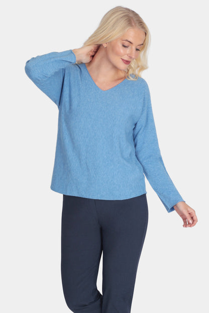 Woman wearing a blue sweater and navy pants on a white background