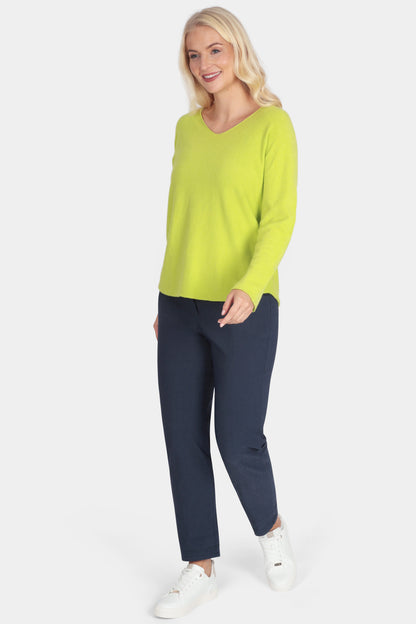 Woman wearing a bright green sweater and navy pants on a white background