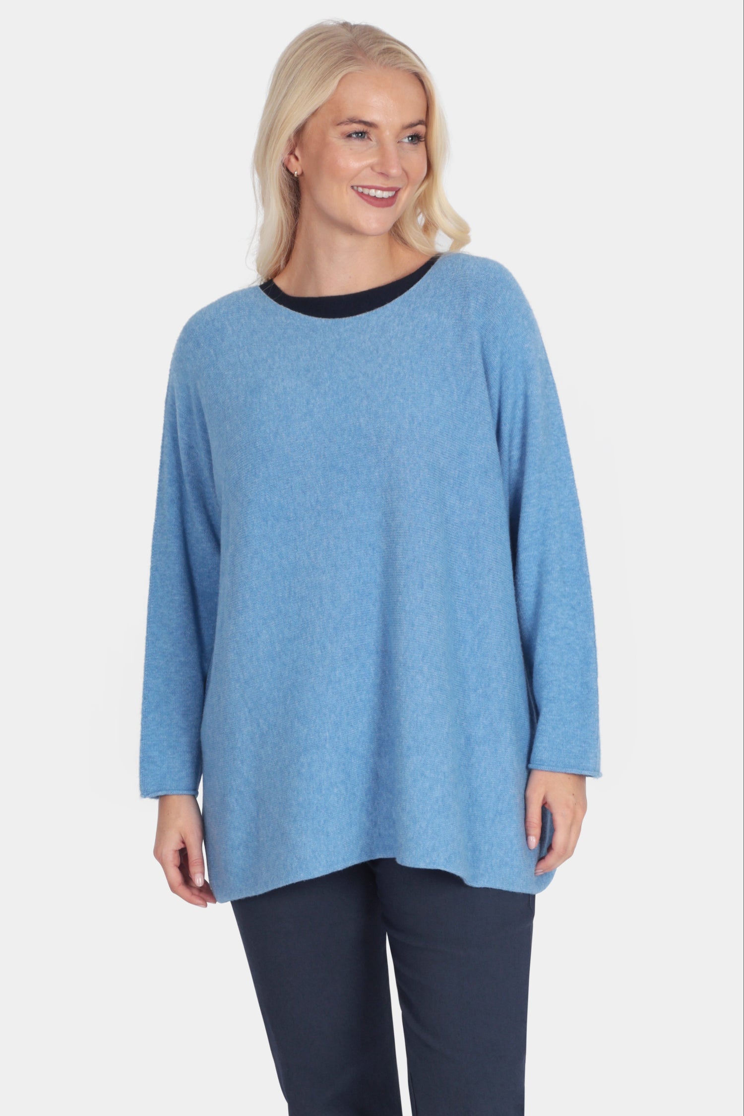 Woman wearing a blue sweater and navy pants on a white background