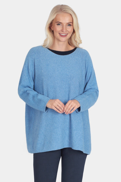 Woman wearing a blue sweater and navy pants on a white background