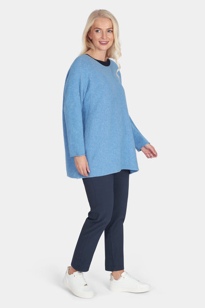 Woman wearing a blue sweater and navy pants on a white background
