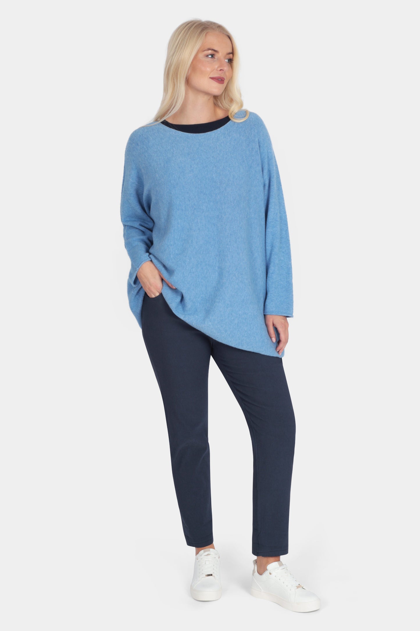 Woman wearing a blue sweater and navy pants on a white background