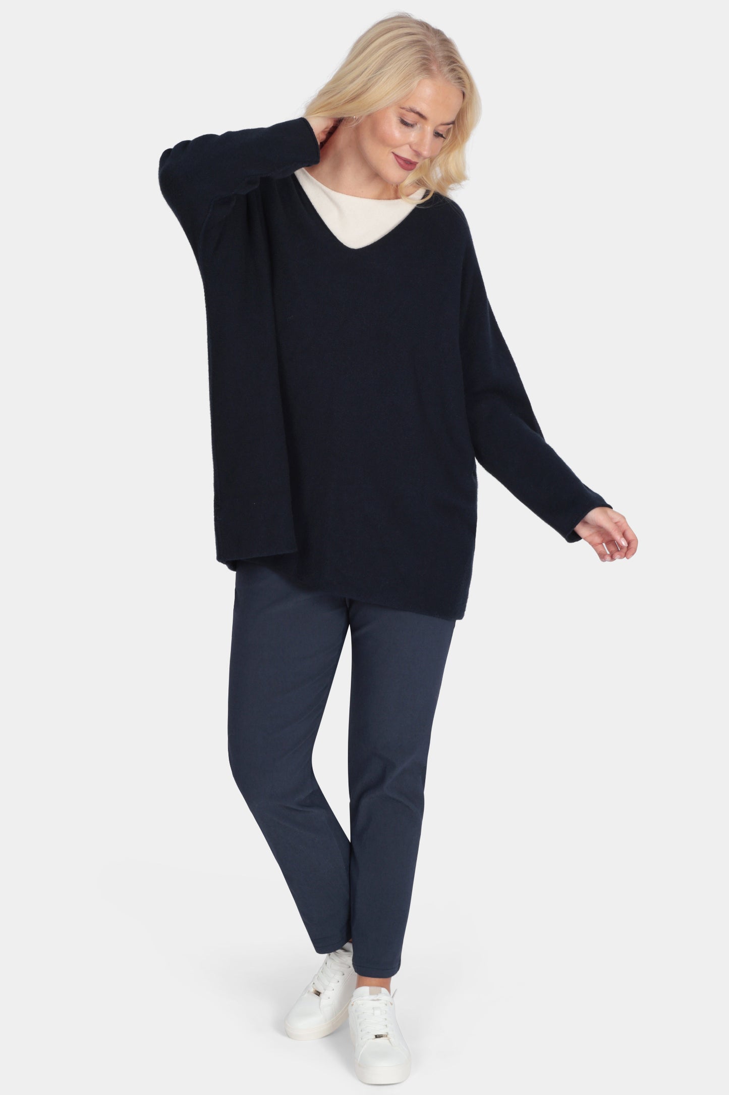 Woman wearing a navy sweater and pants on a white background