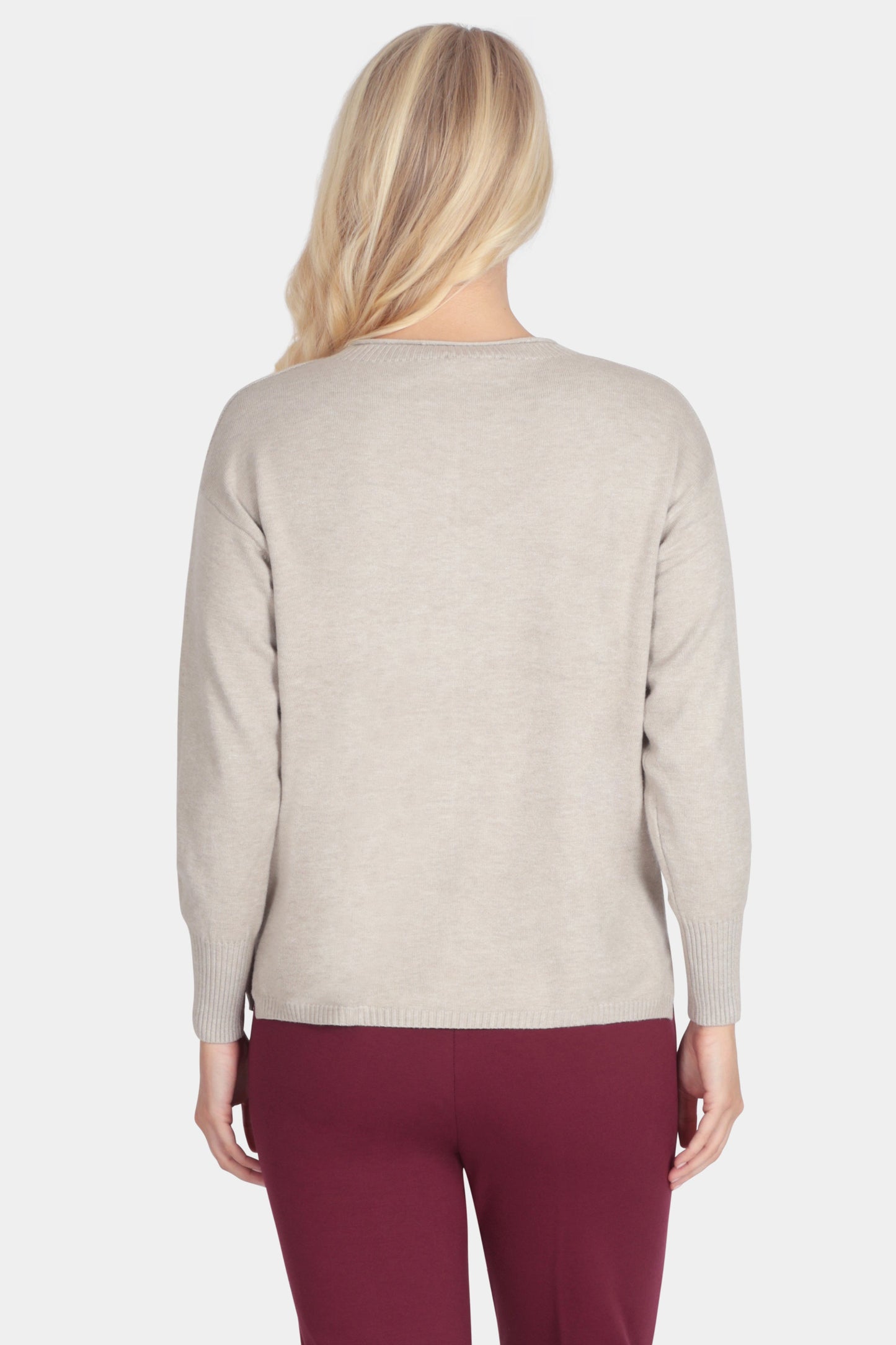 Woman wearing a beige sweater and burgundy pants on a white background