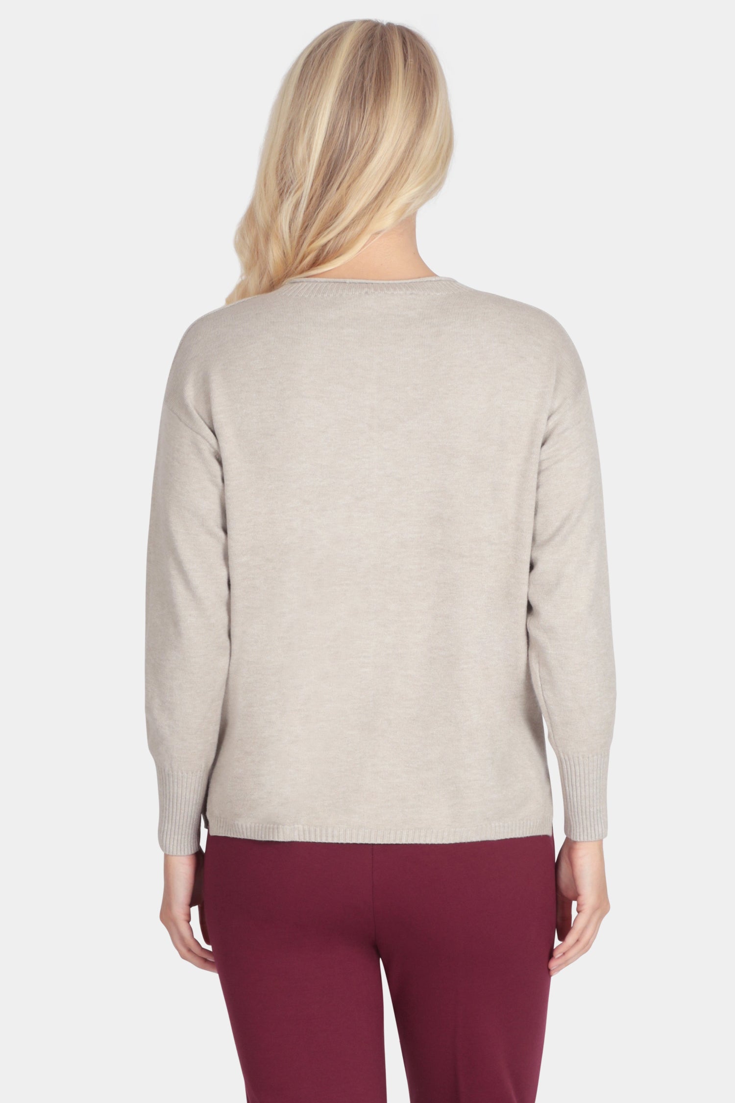 Woman wearing a beige sweater and burgundy pants on a white background