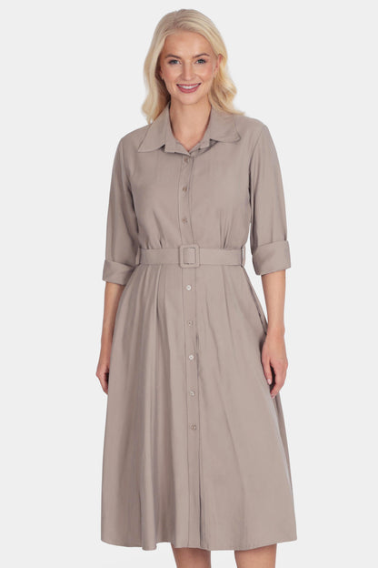 Woman wearing a beige dress with a belt on a white background