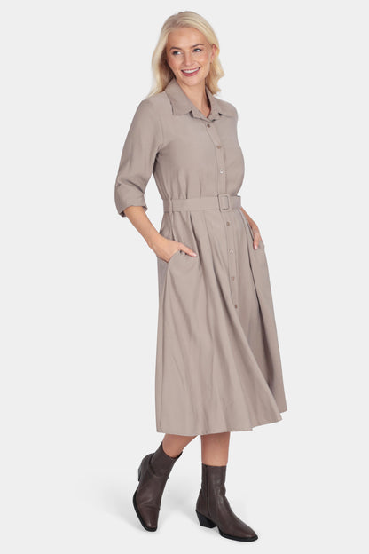 Woman wearing a beige dress with a belt on a white background