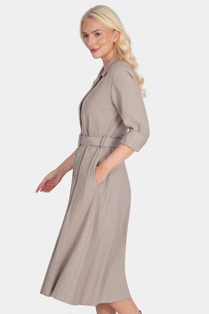 Woman wearing a beige dress with a belt on a white background