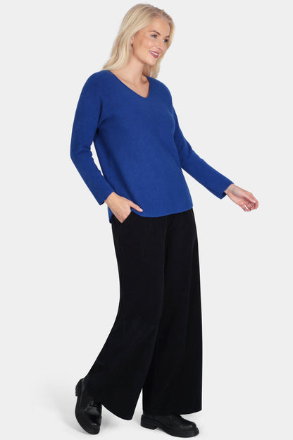 Woman wearing a blue sweater and black pants on a white background