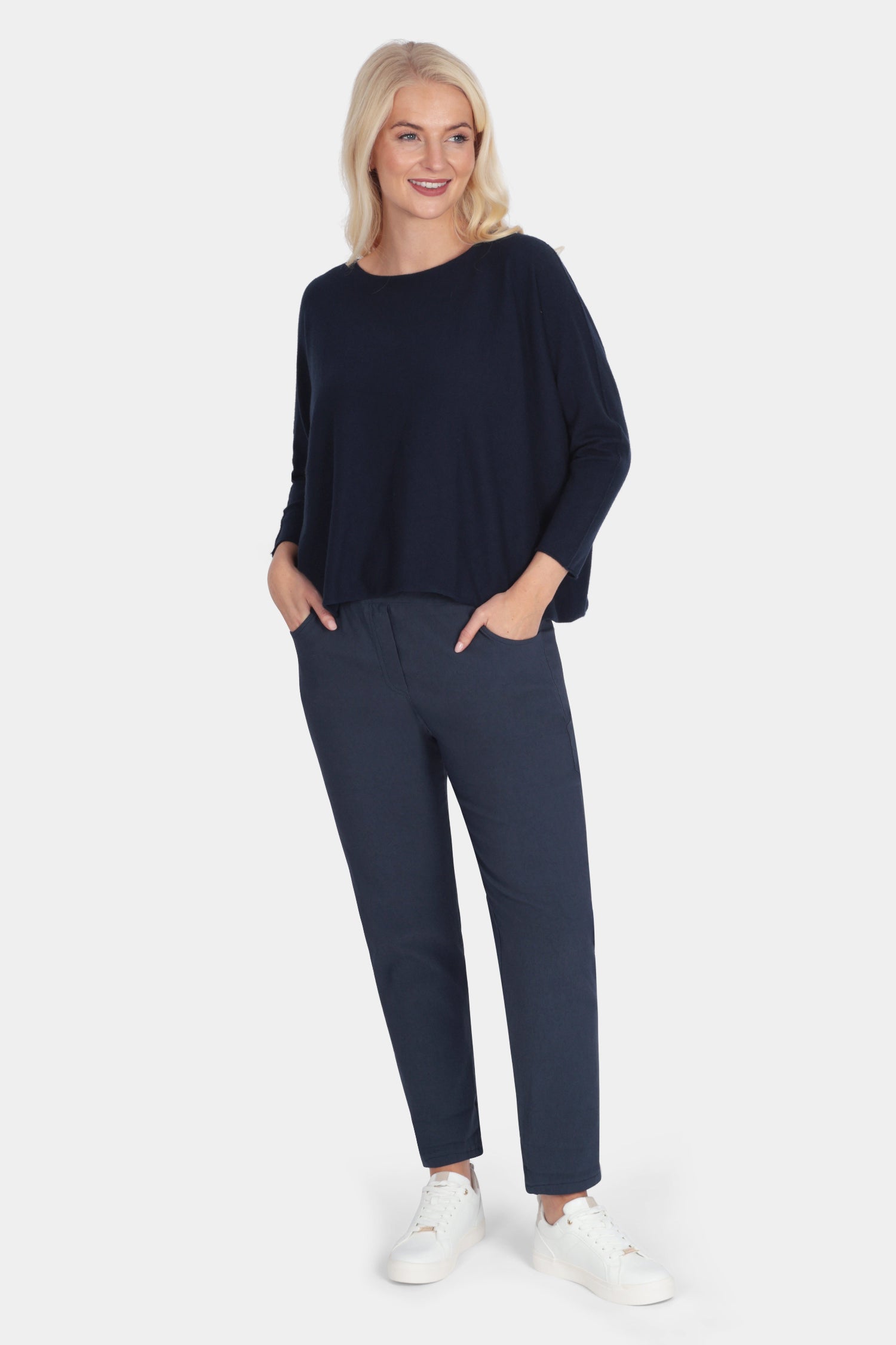 Woman wearing a navy sweater and pants on a white background