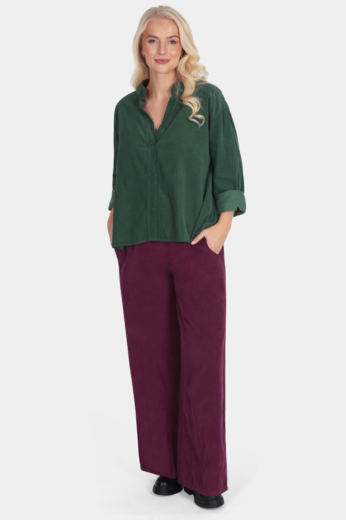 Woman wearing a green top and purple pants on a white background