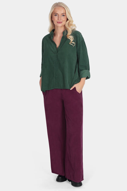 Woman wearing a green top and purple pants on a white background