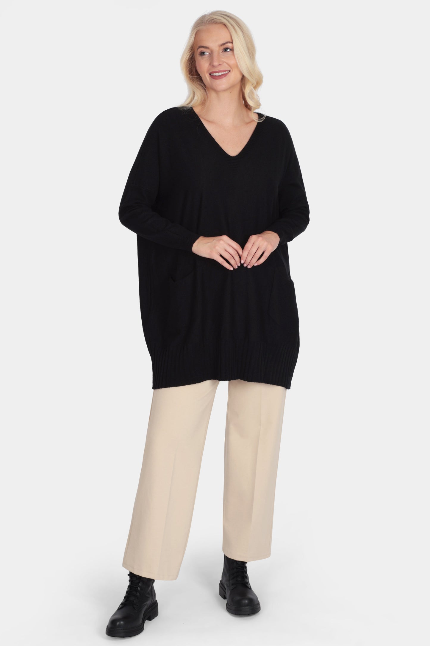 Woman wearing a black sweater and beige pants on a white background