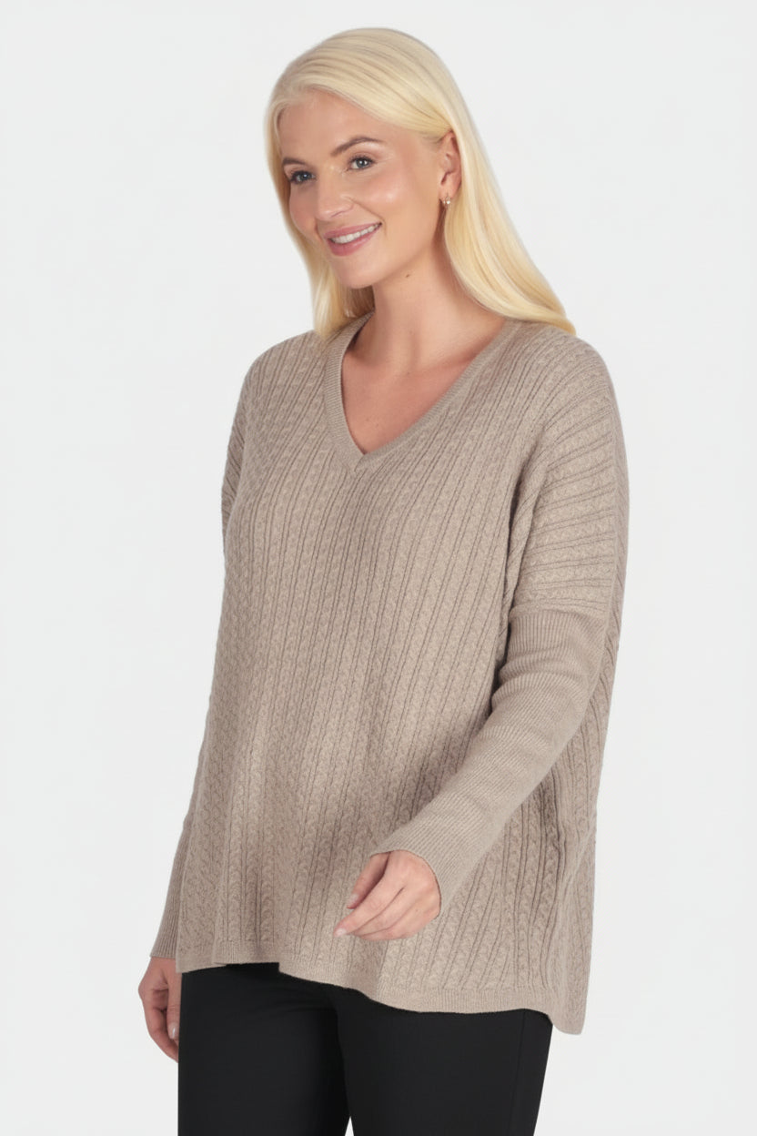 Woman wearing a beige sweater and green pants on a white background