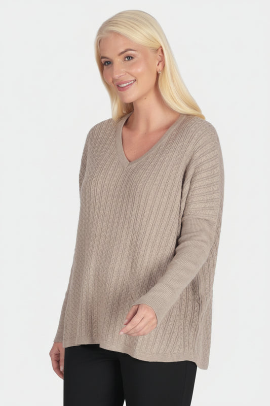 Woman wearing a beige sweater and green pants on a white background