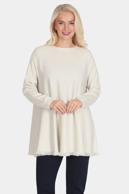 Woman wearing a cream sweater and black pants on a white background