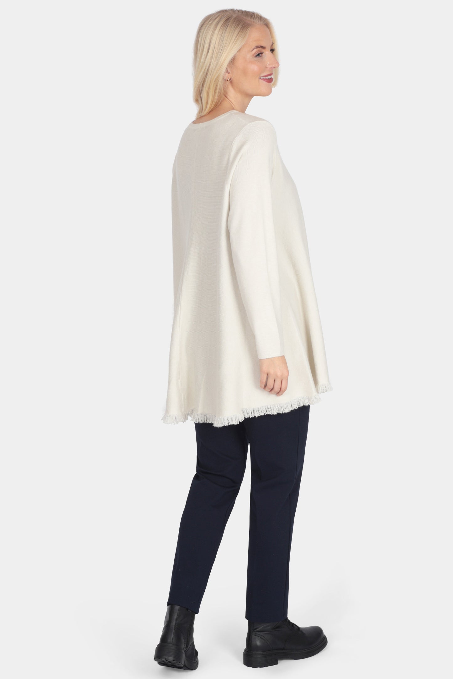 Woman wearing a white poncho over dark pants on a white background