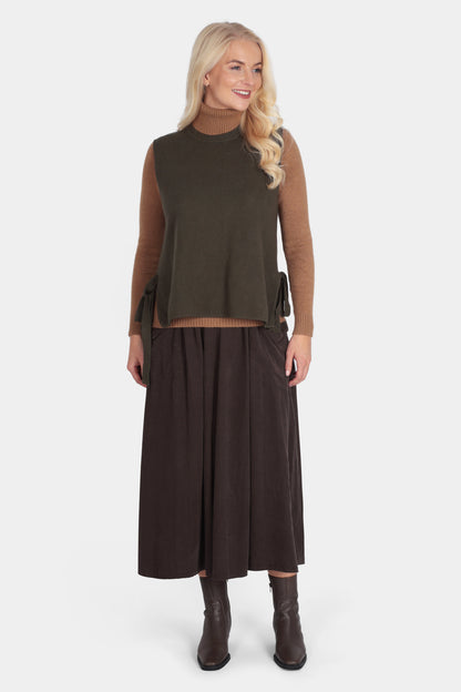 Woman wearing a brown top and dark brown skirt on a white background